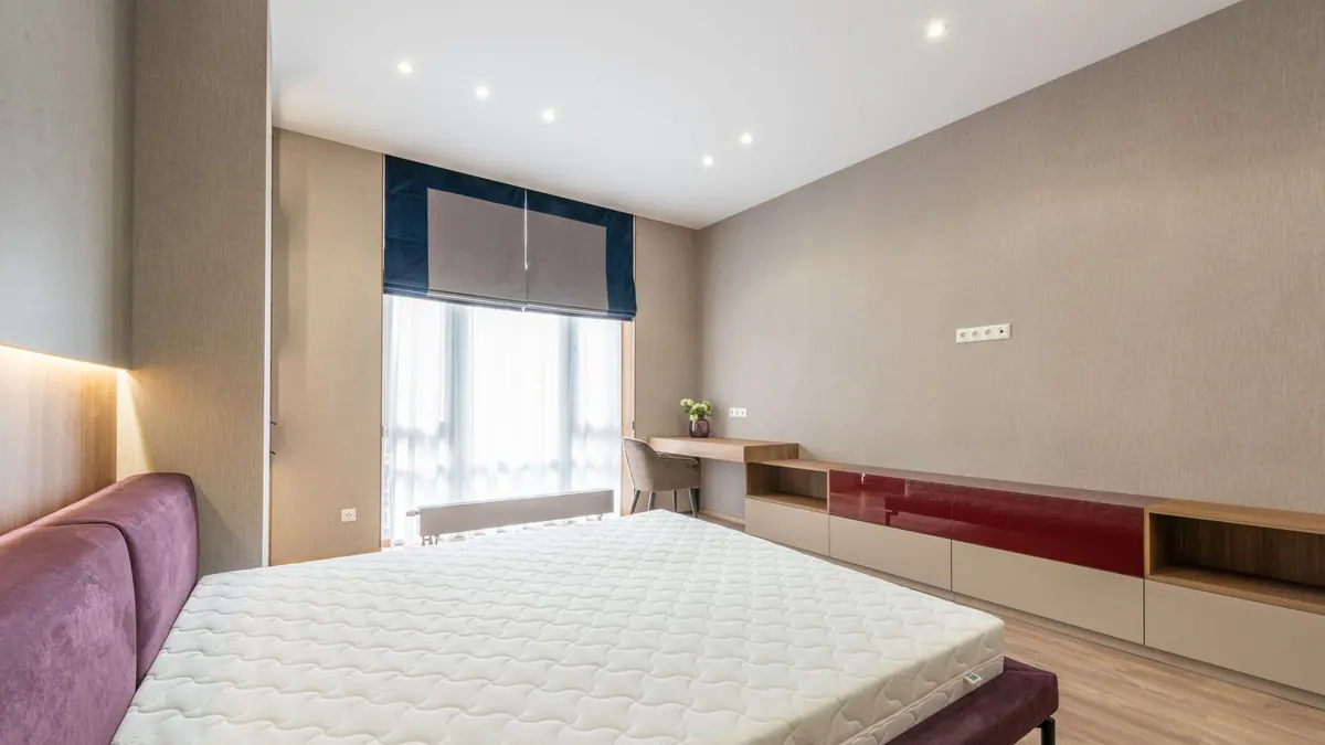 A neatly made bed in a bright bedroom