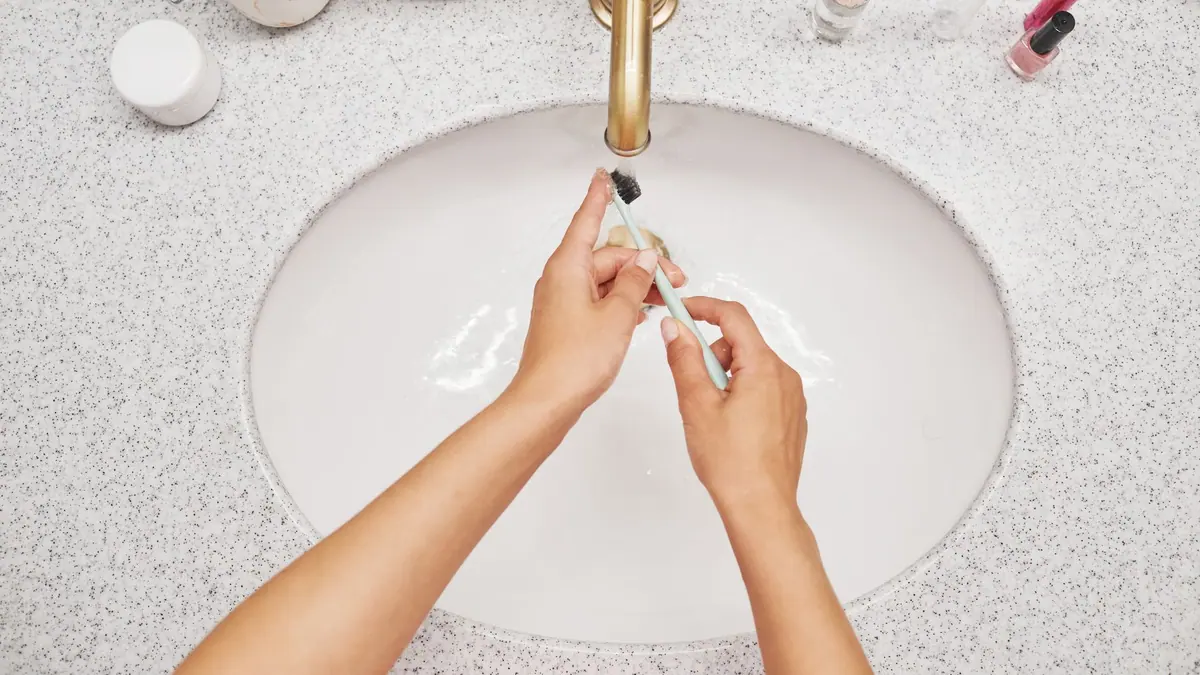 An electric toothbrush standing on a bathroom shelf beside a sink
