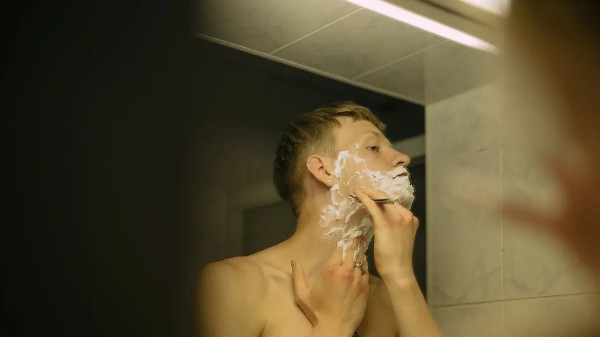 A safety razor and shaving brush on a bathroom shelf