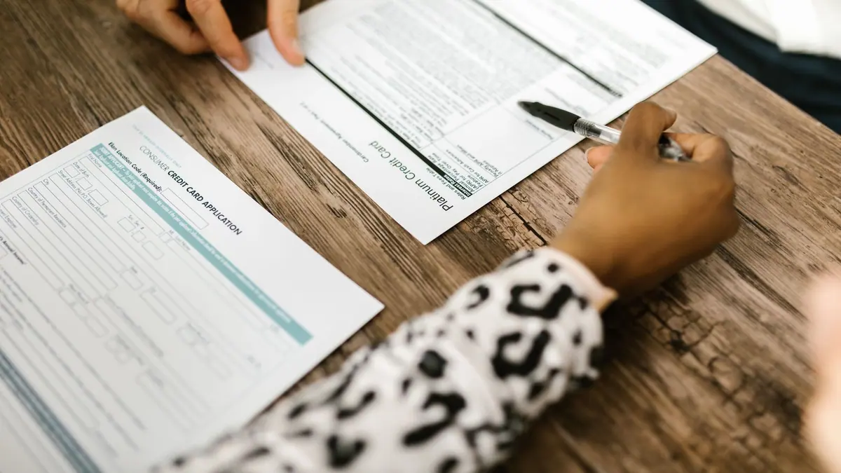 Paperwork and a pen on a desk beside a laptop