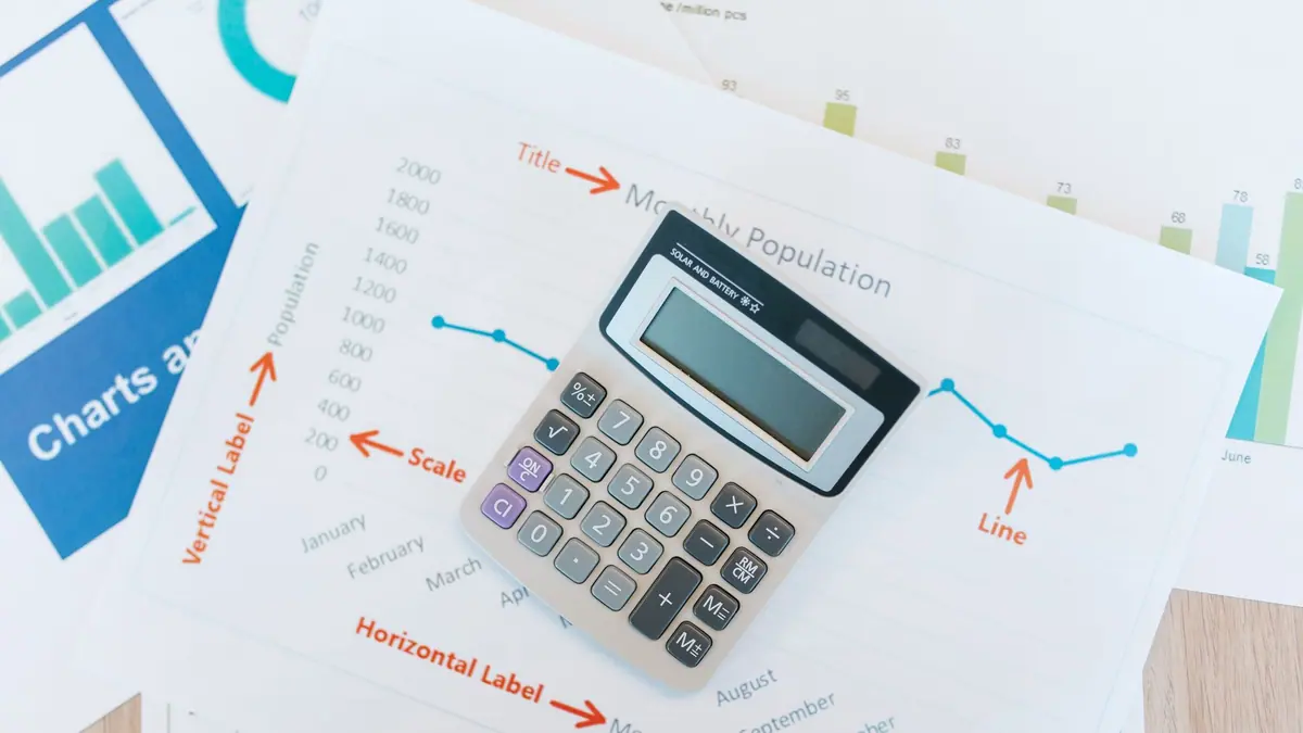 A laptop showing a line chart on a desk beside a notebook