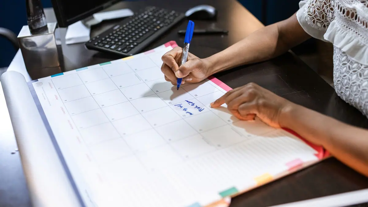 A wall calendar beside a desk lamp