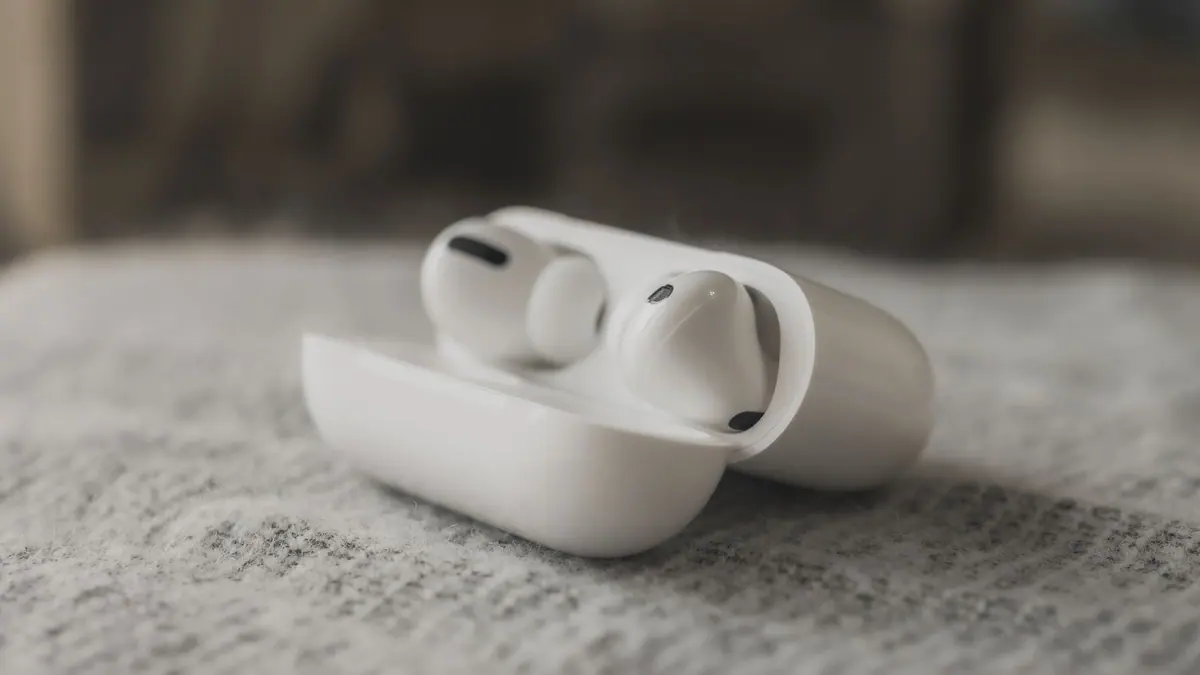 A pair of wireless earbuds beside their charging case on a light surface