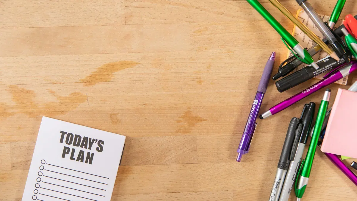 A notebook and pen on a table beside a cup of coffee