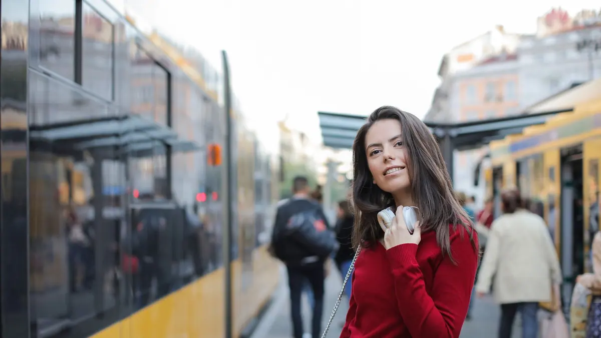 A person wearing over-ear headphones on a busy train platform