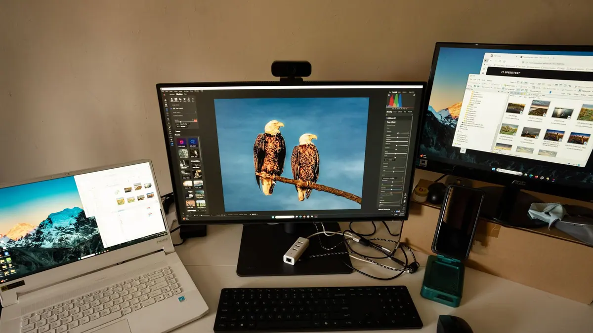 A laptop open on a desk with an external monitor behind it