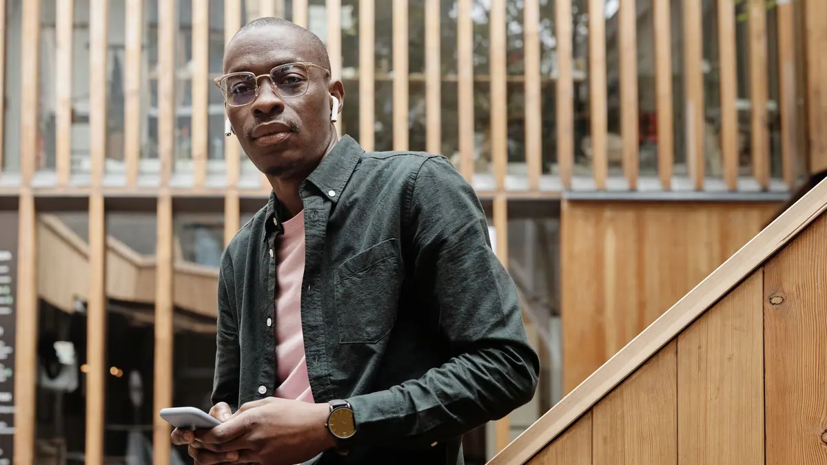 A person wearing glasses and wireless earbuds while walking outdoors