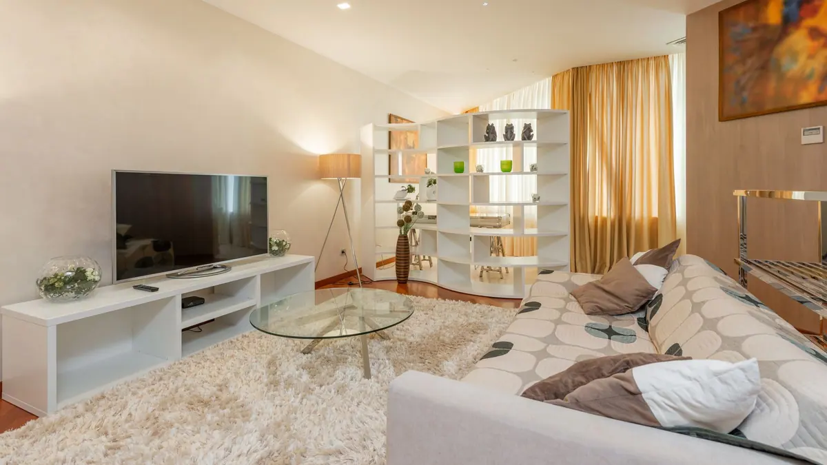 A large television in a bright living room with daylight from a window