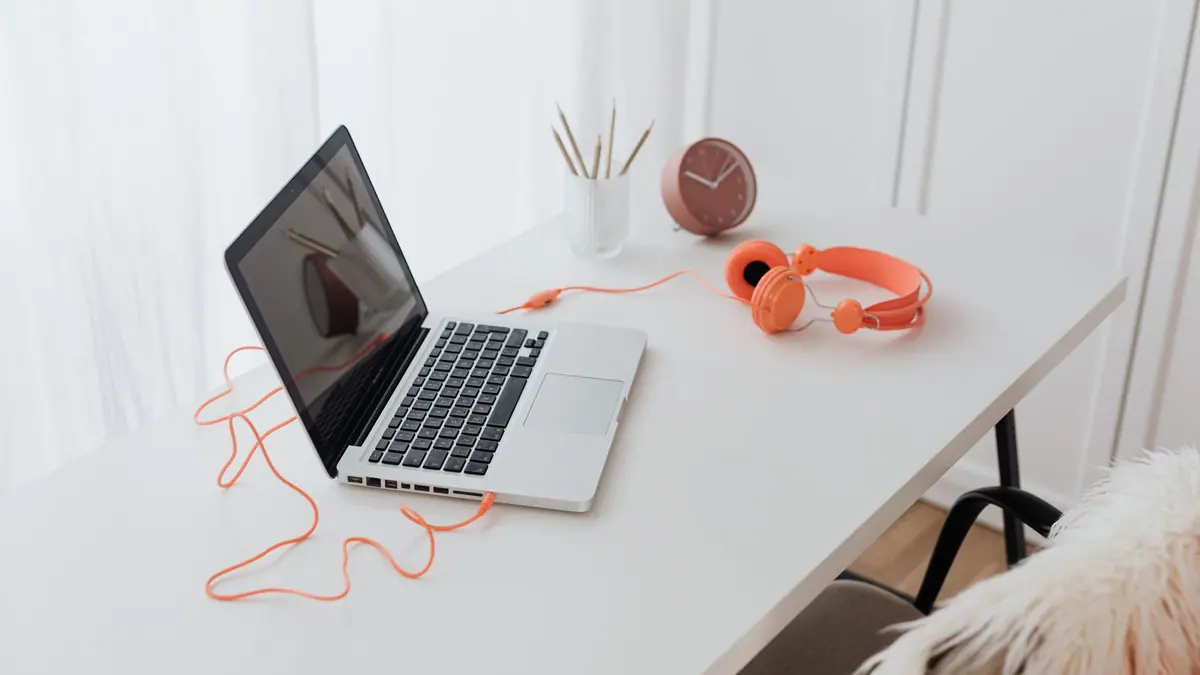 A desk setup with wired headphones plugged into a computer