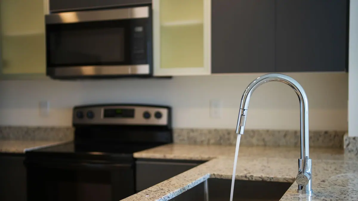 An air fryer basket being cleaned at a kitchen sink
