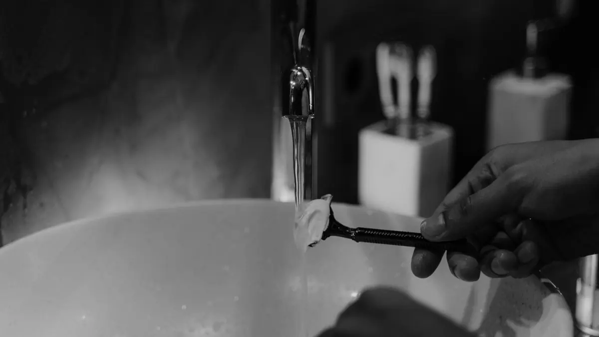 A razor and shaving cream beside a bathroom sink