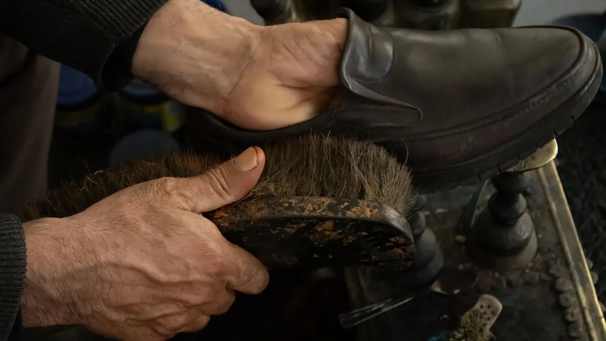 Boots being cleaned with a brush and polish
