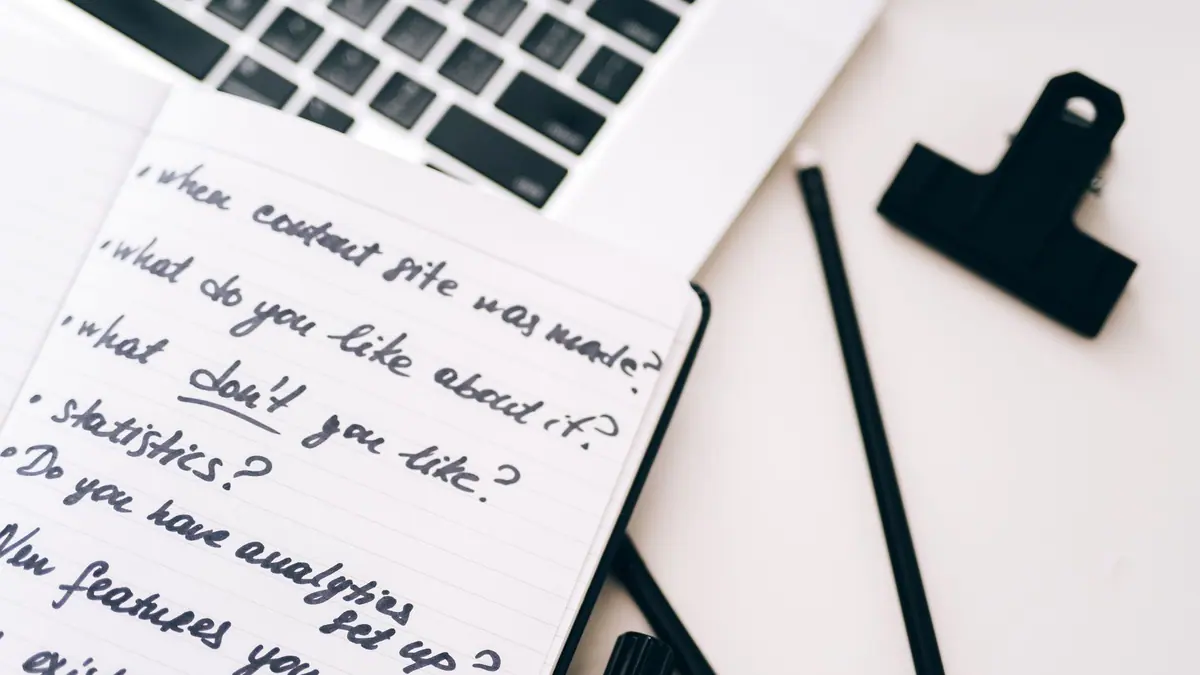 A notebook with handwritten notes beside a laptop